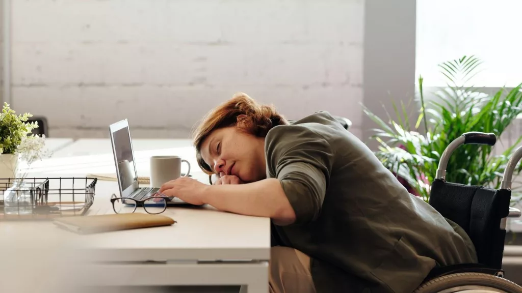 A girl sleeping on desk while working on laptop